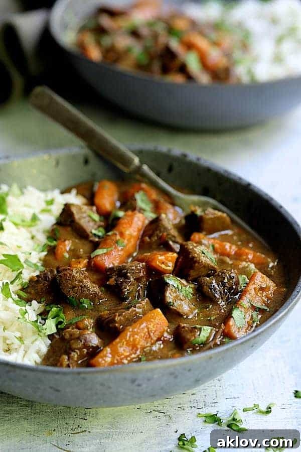Close-up photo of a single serving of the hearty Pressure Cooker Indian Curry Beef Stew in a gray bowl, showcasing its rich texture.