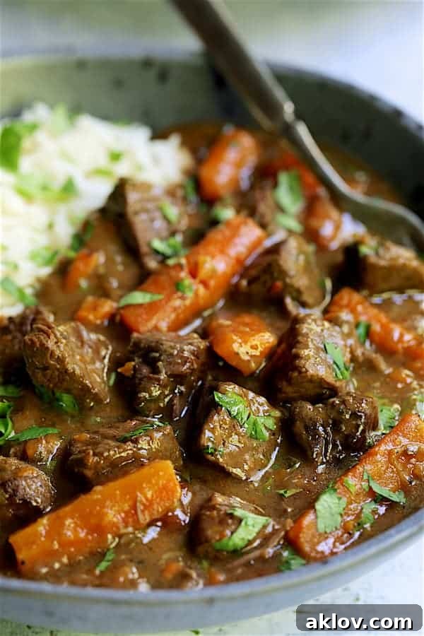 Close-up photo of one serving of Pressure Cooker Indian Curry Beef Stew in a gray bowl, emphasizing its vibrant colors and textures.