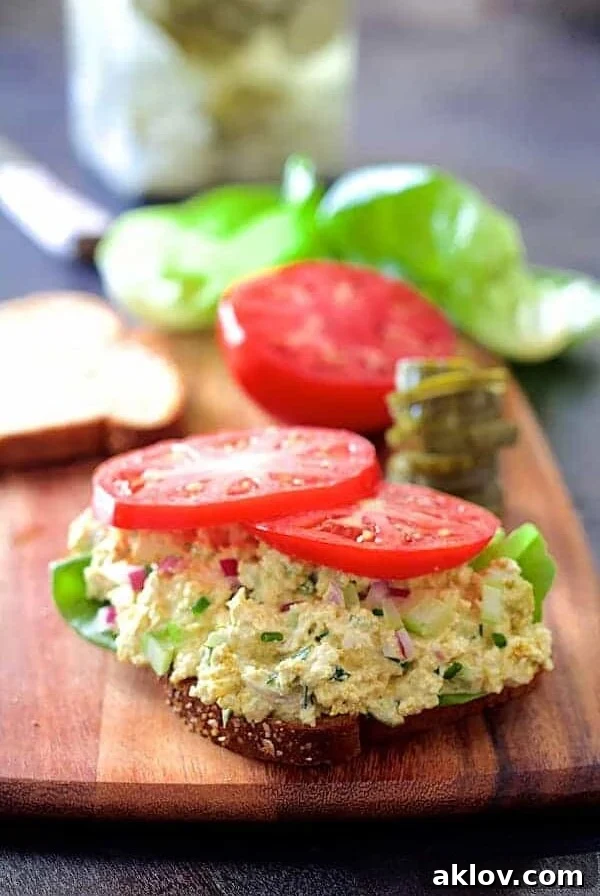 Tofu Salad on slice of bread topped with tomato slices.