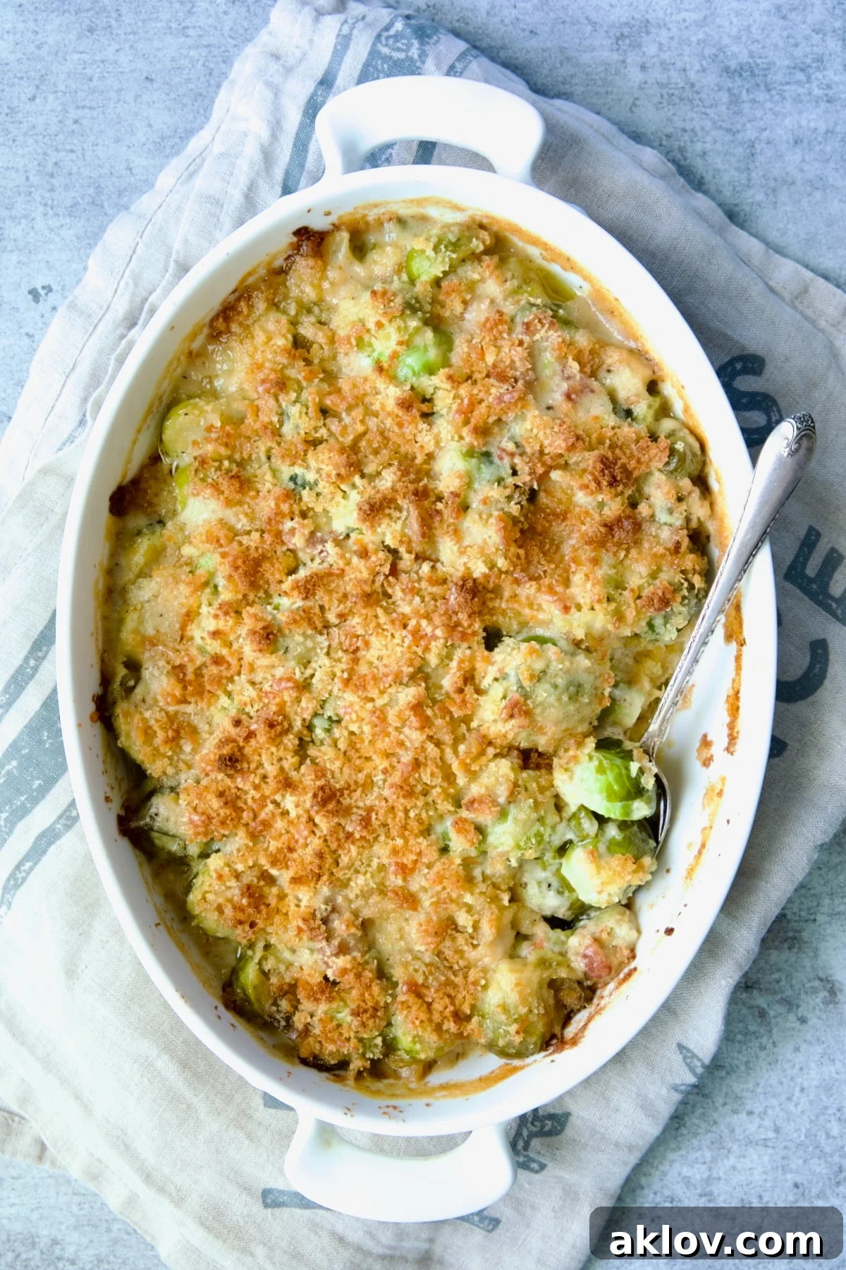 Brussels Sprouts Gratin in oval baking dish with spoon scooping some up.