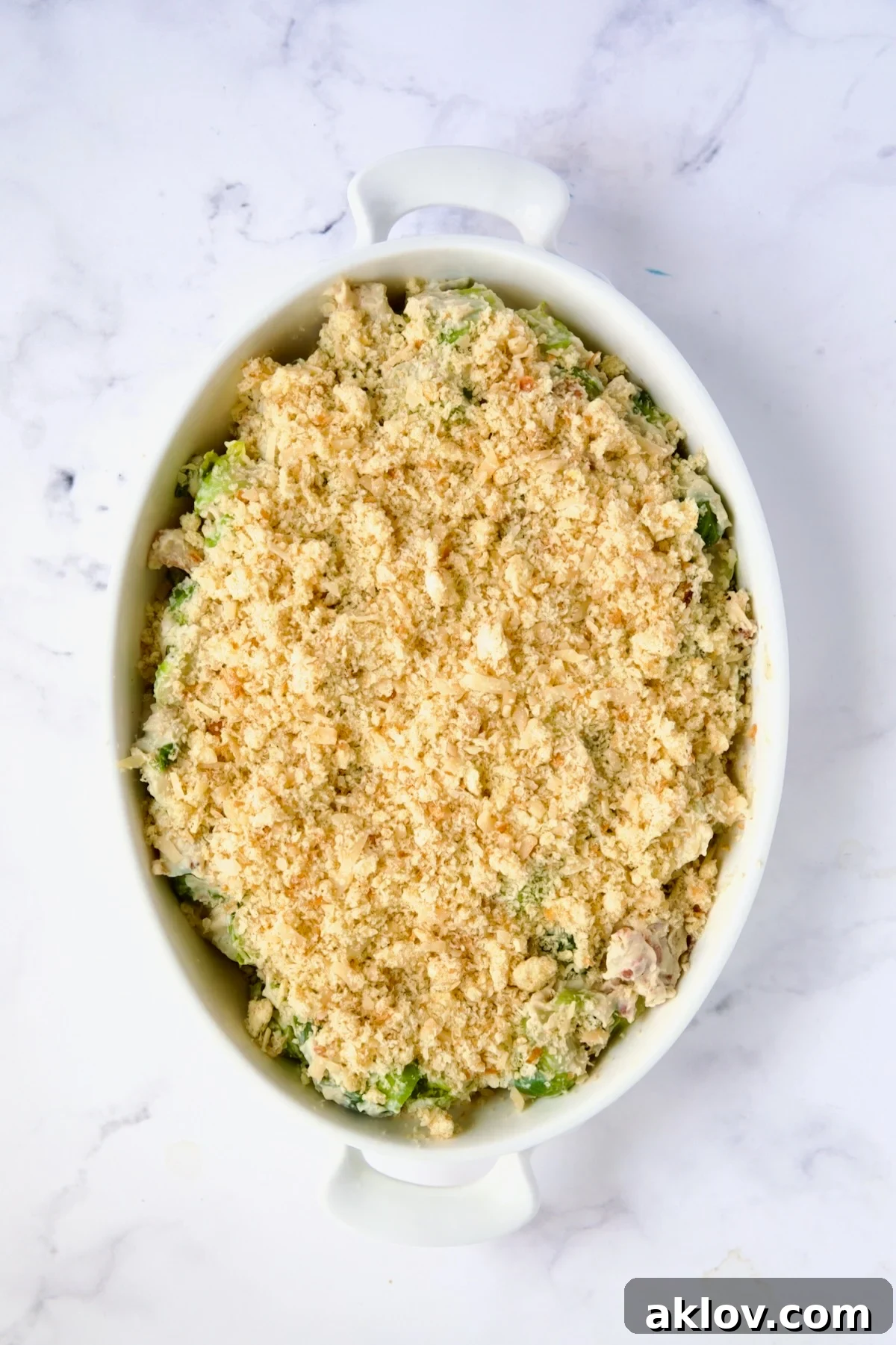 The Brussels Sprouts Gratin fully assembled with its golden breadcrumb topping, nestled in an oval baking dish, ready for baking.