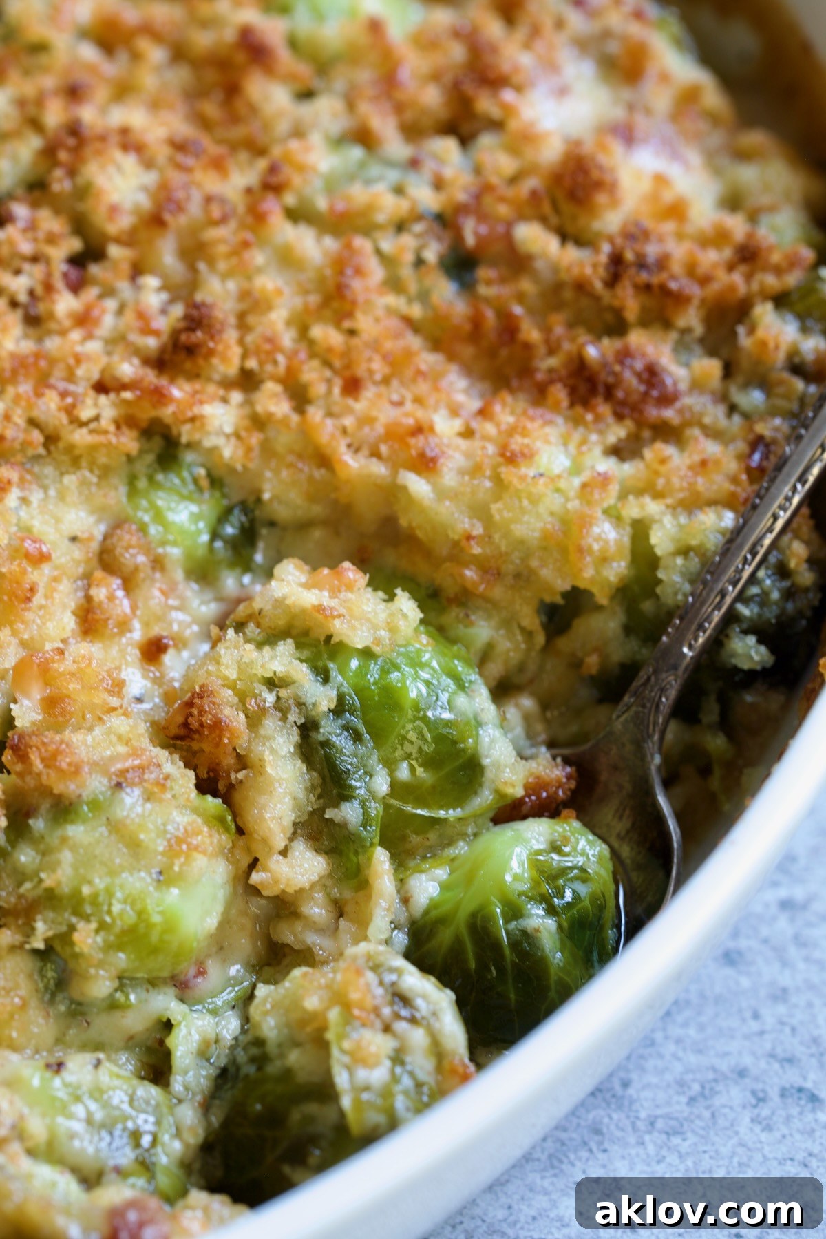 Brussels Sprouts Gratin in oval baking dish with spoon scooping some up.