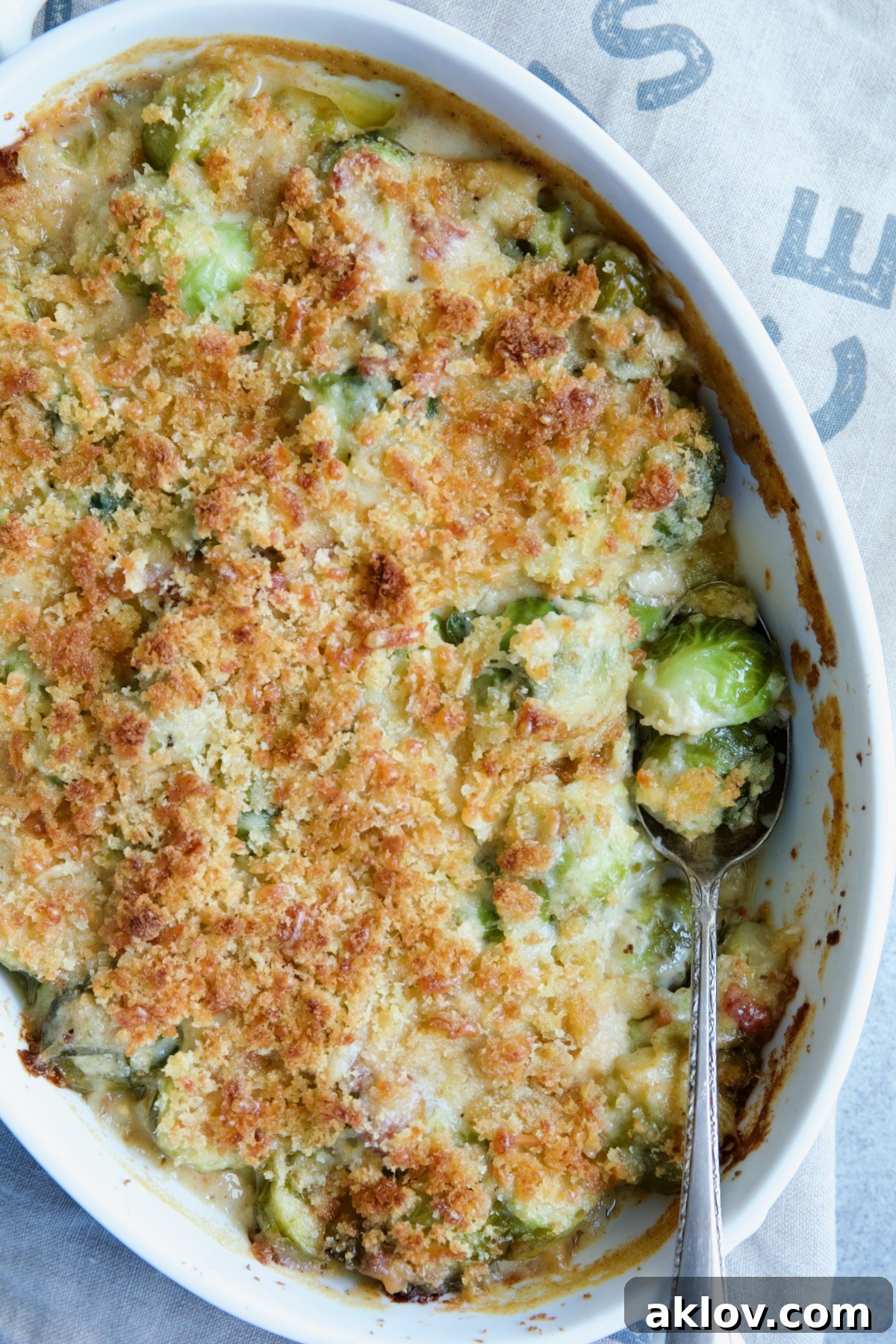 Brussels Sprouts Gratin in oval baking dish with spoon scooping some up.