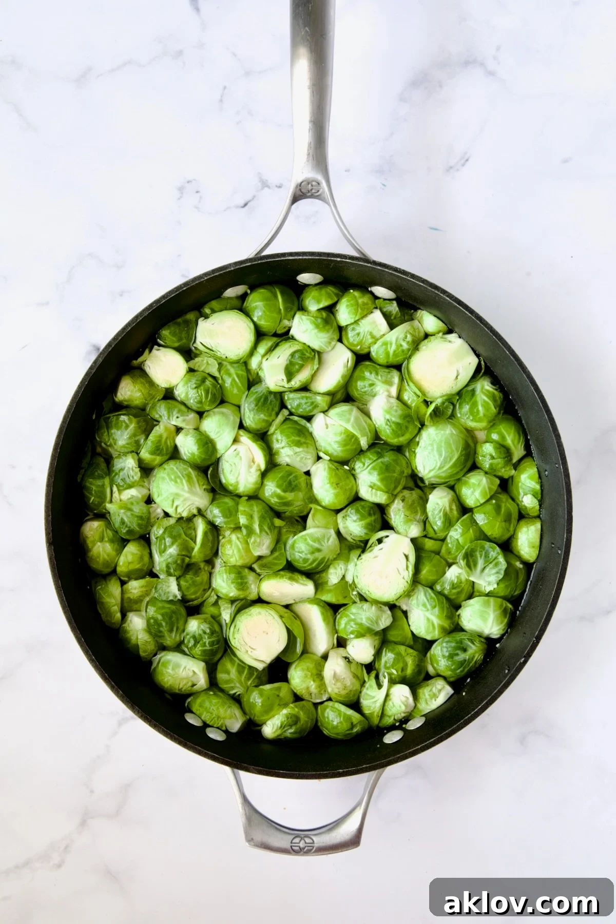 Halved Brussels sprouts glistening in a nonstick skillet after being prepared.