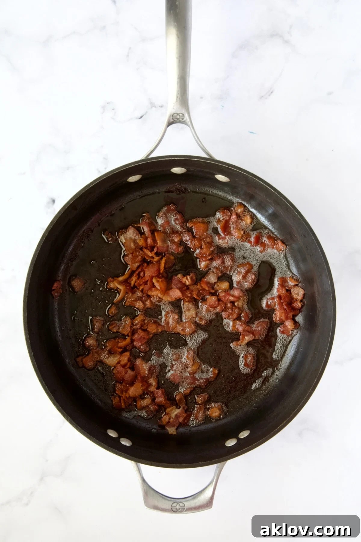 Perfectly cooked, crispy bacon strips resting in a nonstick skillet, having rendered their delicious drippings.