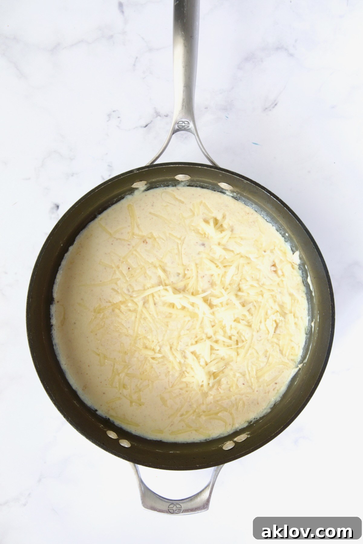 Cheese added to cream sauce in nonstick skillet.