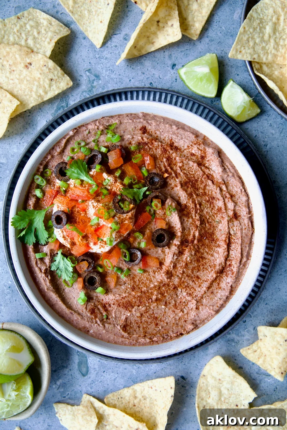 Zesty Black Bean Delight 9 Overhead shot of a bowl of Black Bean Dip surrounded by crispy tortilla chips and fresh lime wedges, showcasing its vibrant texture and inviting presentation.