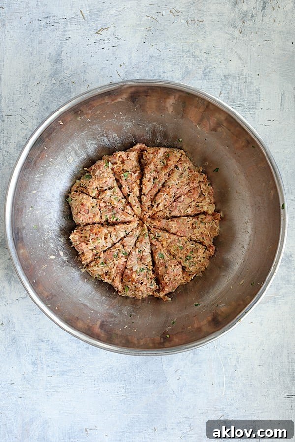 Overhead shot of the meat filling in a stainless steel bowl, now neatly divided into 12 equal sections for consistent cabbage rolls.