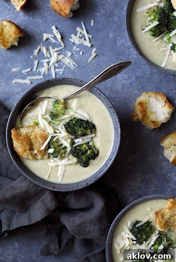 Broccoli Gruyere Soup in gray bowl with croutons garnished with broccoli florets.