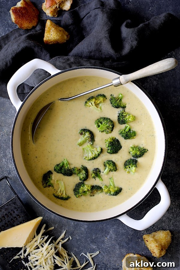 Broccoli Gruyere Soup with Torn Garlic Croutons - Overhead shot of soup in white Dutch oven on dark blue background, ready to be served.