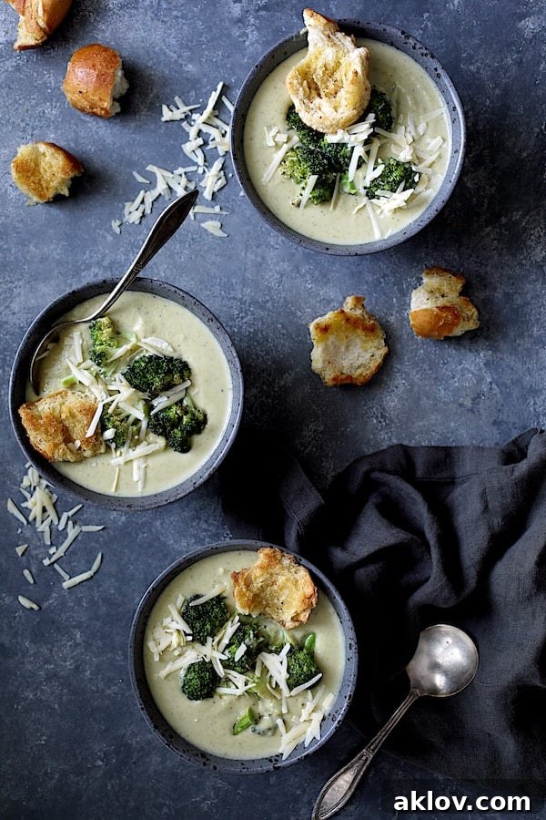 Broccoli Gruyere Soup with Torn Garlic Croutons - Overhead shot of three bowls of the soup garnished with cheese, broccoli and croutons, ready for a dinner party.