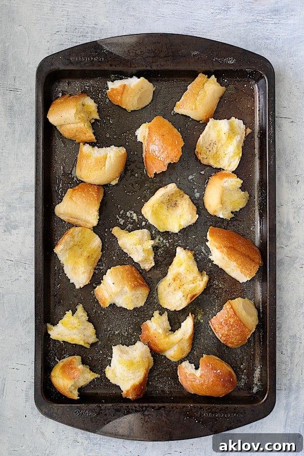 Overhead shot of perfectly baked torn garlic croutons on a baking sheet, golden and crispy.