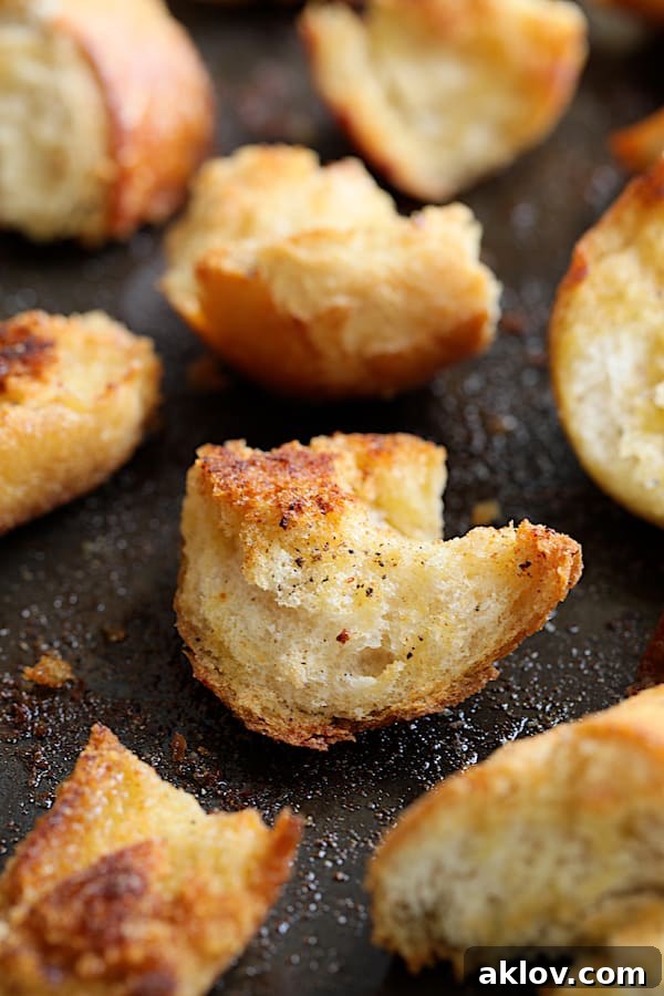 Close-up shot of a single perfectly baked torn garlic crouton, showcasing its golden crust and rustic texture.