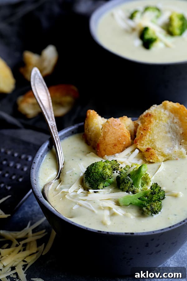Broccoli Gruyere Soup with Torn Garlic Croutons - Straight-on close-up shot of soup garnished with roasted broccoli, grated cheese, and torn croutons, showcasing its appetizing presentation.