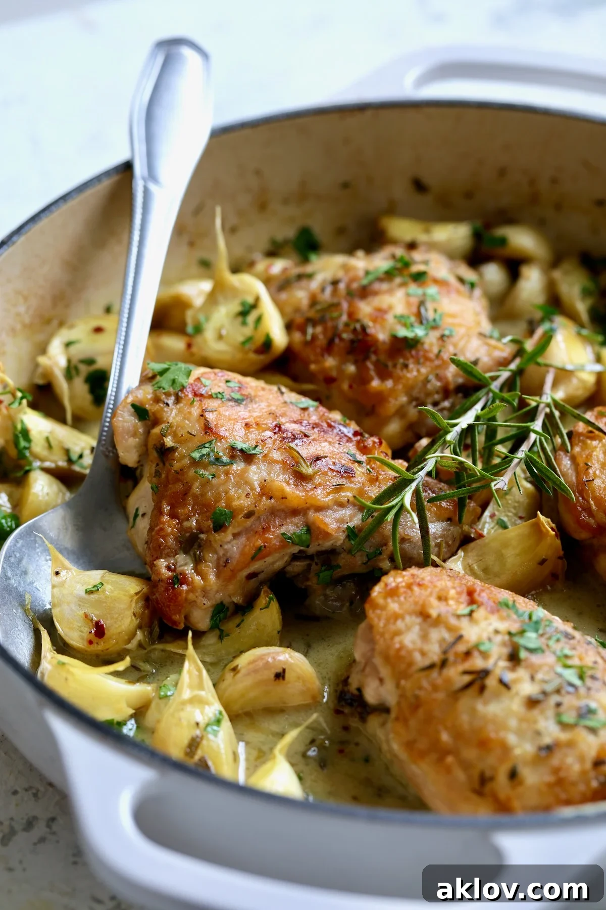 Four servings of 40 Clove Garlic Chicken in white enamel cast iron skillet.