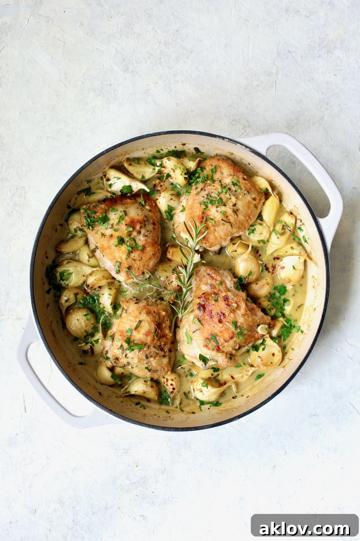 Liquid ingredients added to unpeeled garlic cloves and browned chicken thighs in white enamel cast iron skillet.