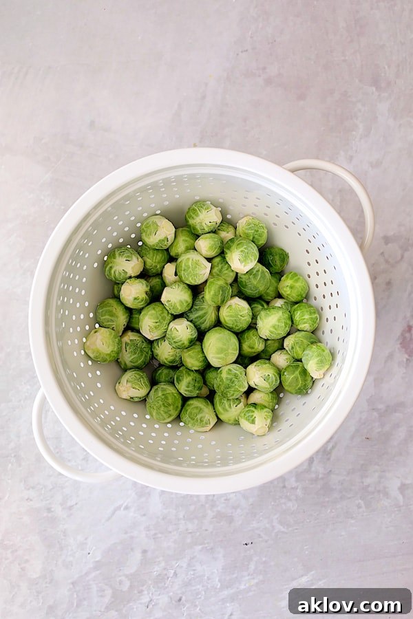Sweet Heat Orange Glazed Brussels Sprouts 3 Photo of uncooked Brussels Sprouts in a white colander, ready for preparation.
