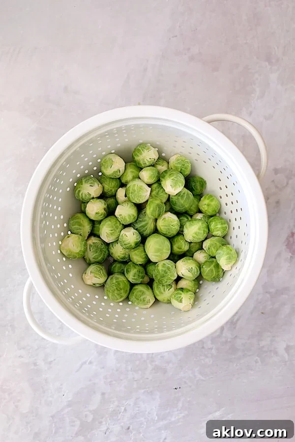Photo of uncooked Brussels Sprouts in white colander.