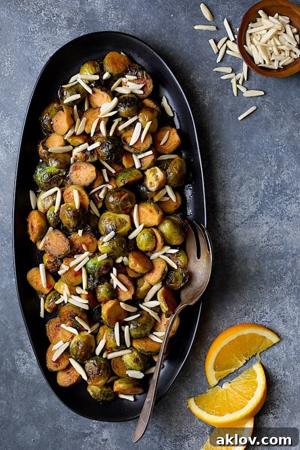 Photo of Pan-Roasted Brussels Sprouts with Thai Sweet Chili Orange Glaze with slivered almonds and orange wedges.
