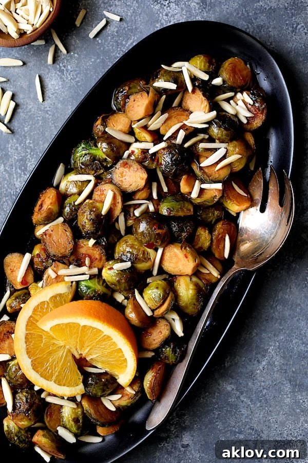Close-up photo of Pan-Roasted Brussels Sprouts with Thai Sweet Chili Orange Glaze garnished with two orange wedges.