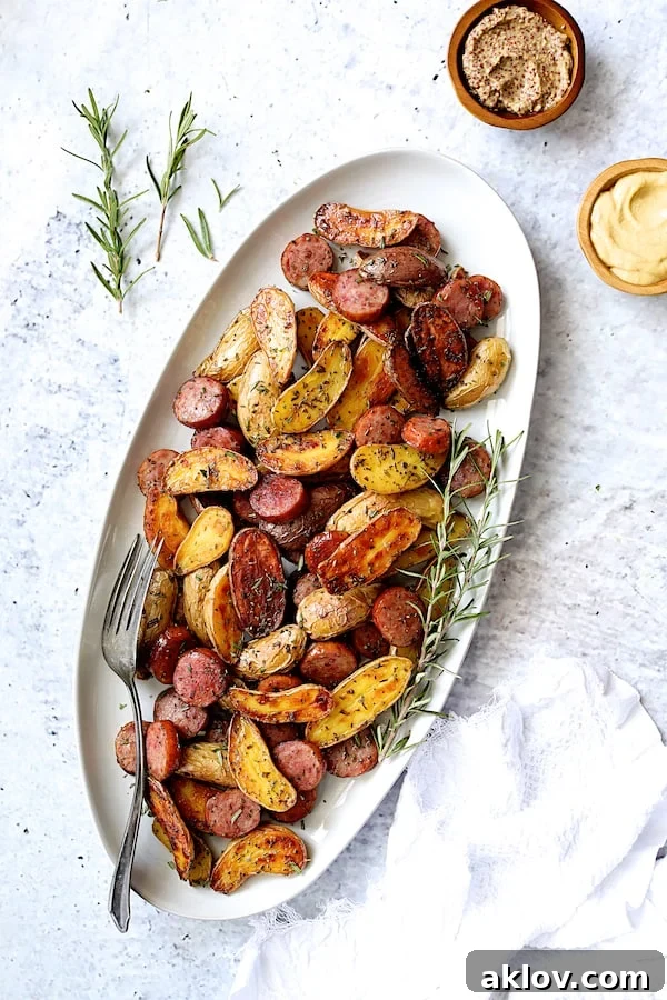 Close-up of golden brown Duck Fat and Rosemary Roasted Fingerling Potatoes on a white oval platter, garnished with fresh rosemary.