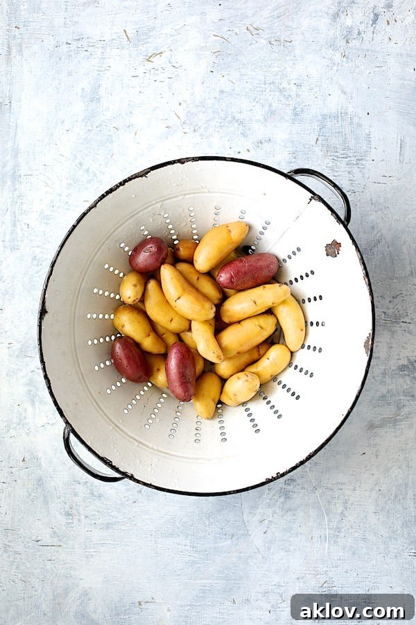 Vintage colander filled with fresh fingerling potatoes, ready for preparation.