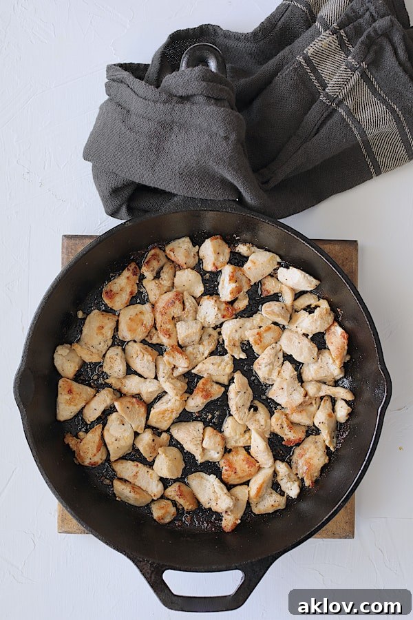Close-up photo of chicken pieces being beautifully browned in a hot cast iron skillet, creating a flavorful base for the pot pie.