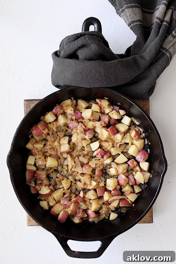 Onions and cubed potatoes gently cooking and softening in the cast iron skillet, building layers of flavor for the pot pie filling.