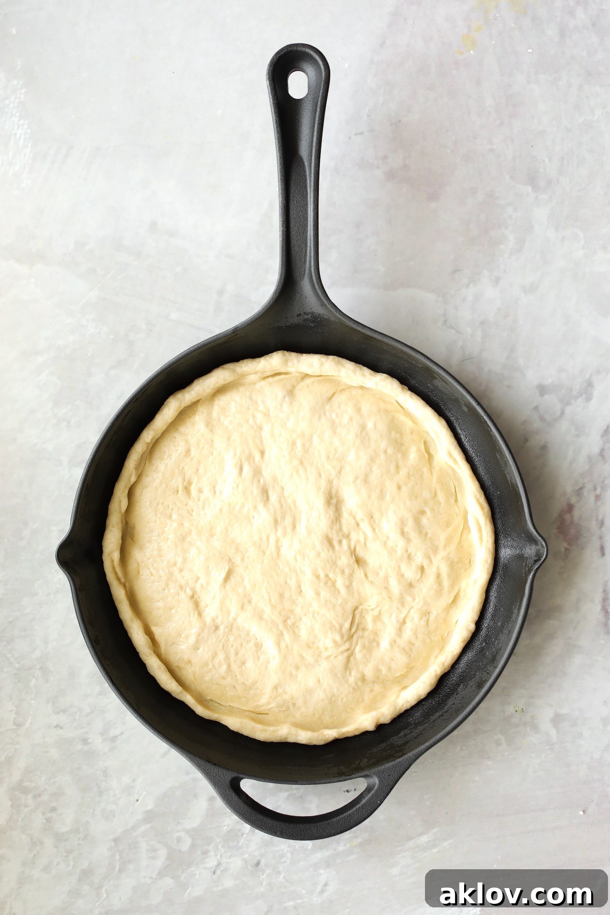 Pizza dough in cast iron skillet before toppings are added.