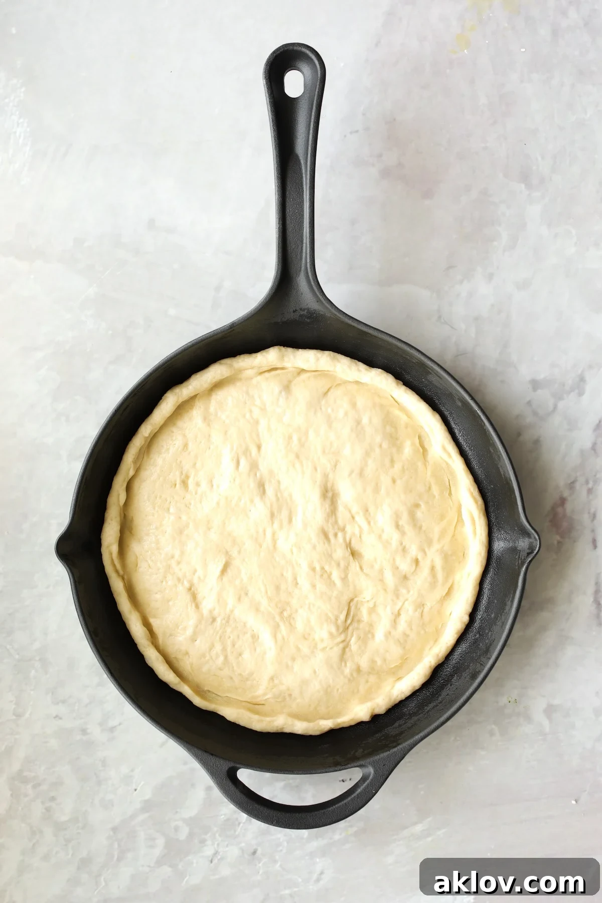 Pizza dough perfectly formed within the cast iron skillet, ready for toppings.