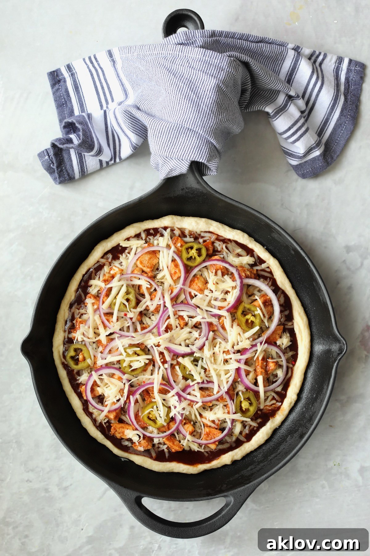 Topped pizza in cast iron skillet before being baked.