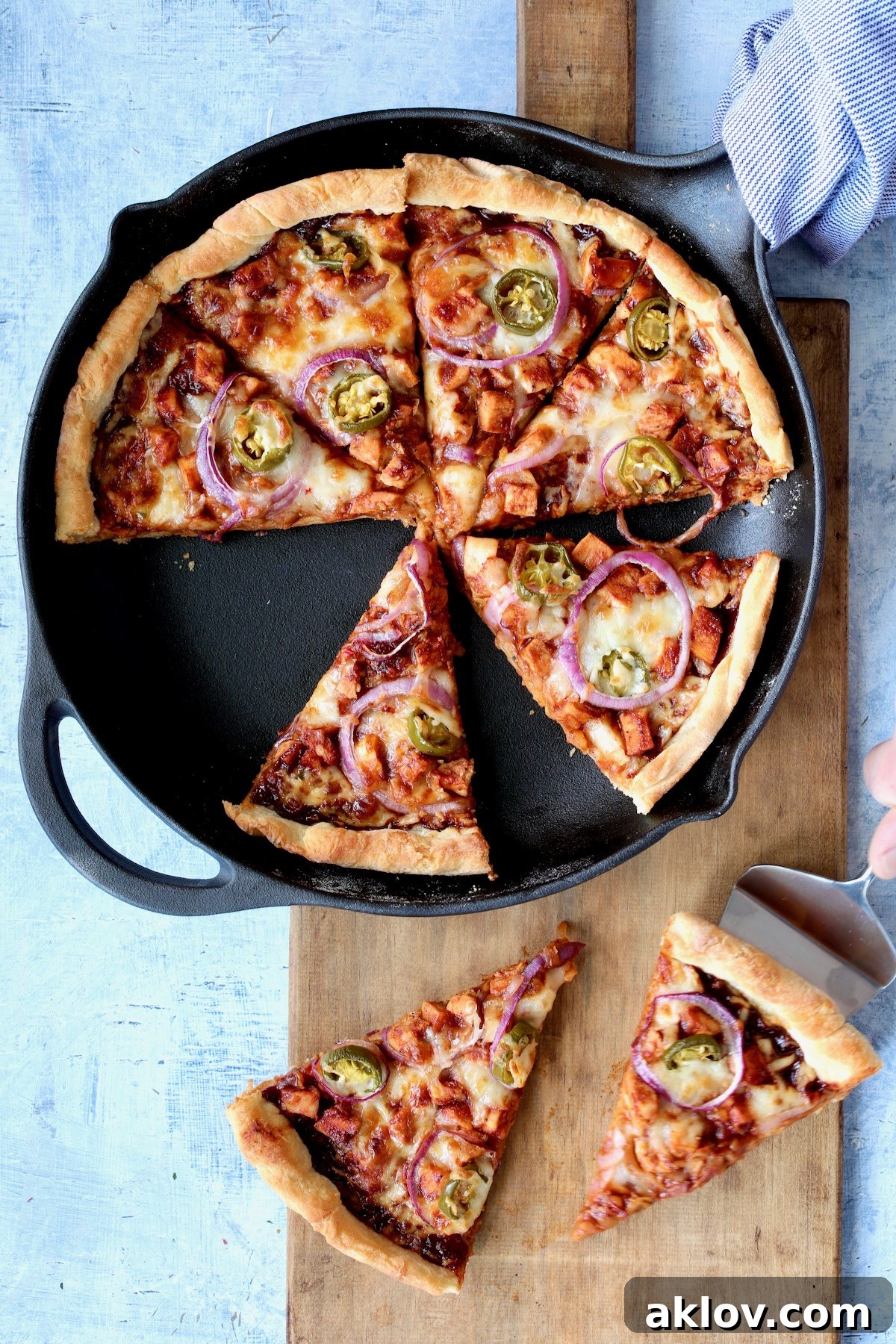 Topped pizza in cast iron skillet after being baked and cut into wedges.
