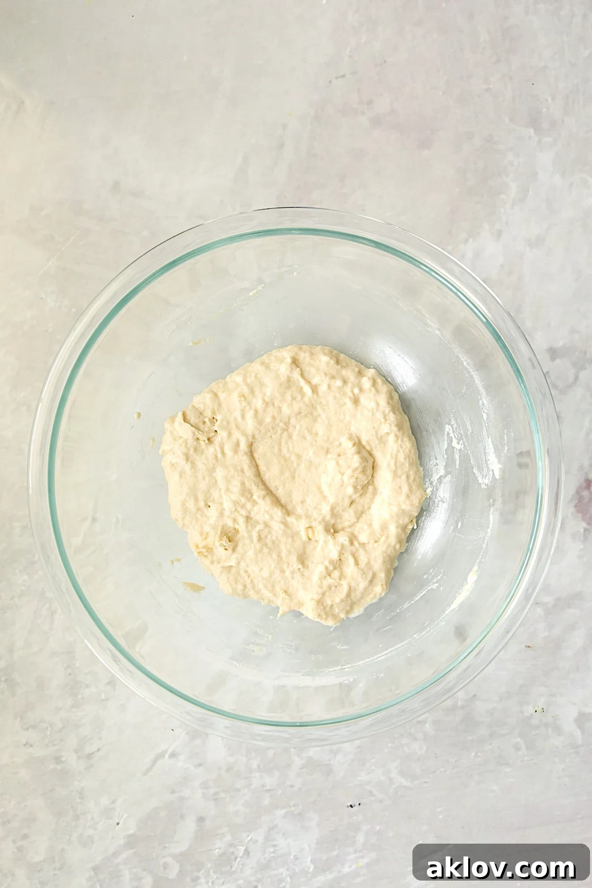 Shaggy pizza dough in a glass bowl immediately after initial mixing of wet and dry ingredients.