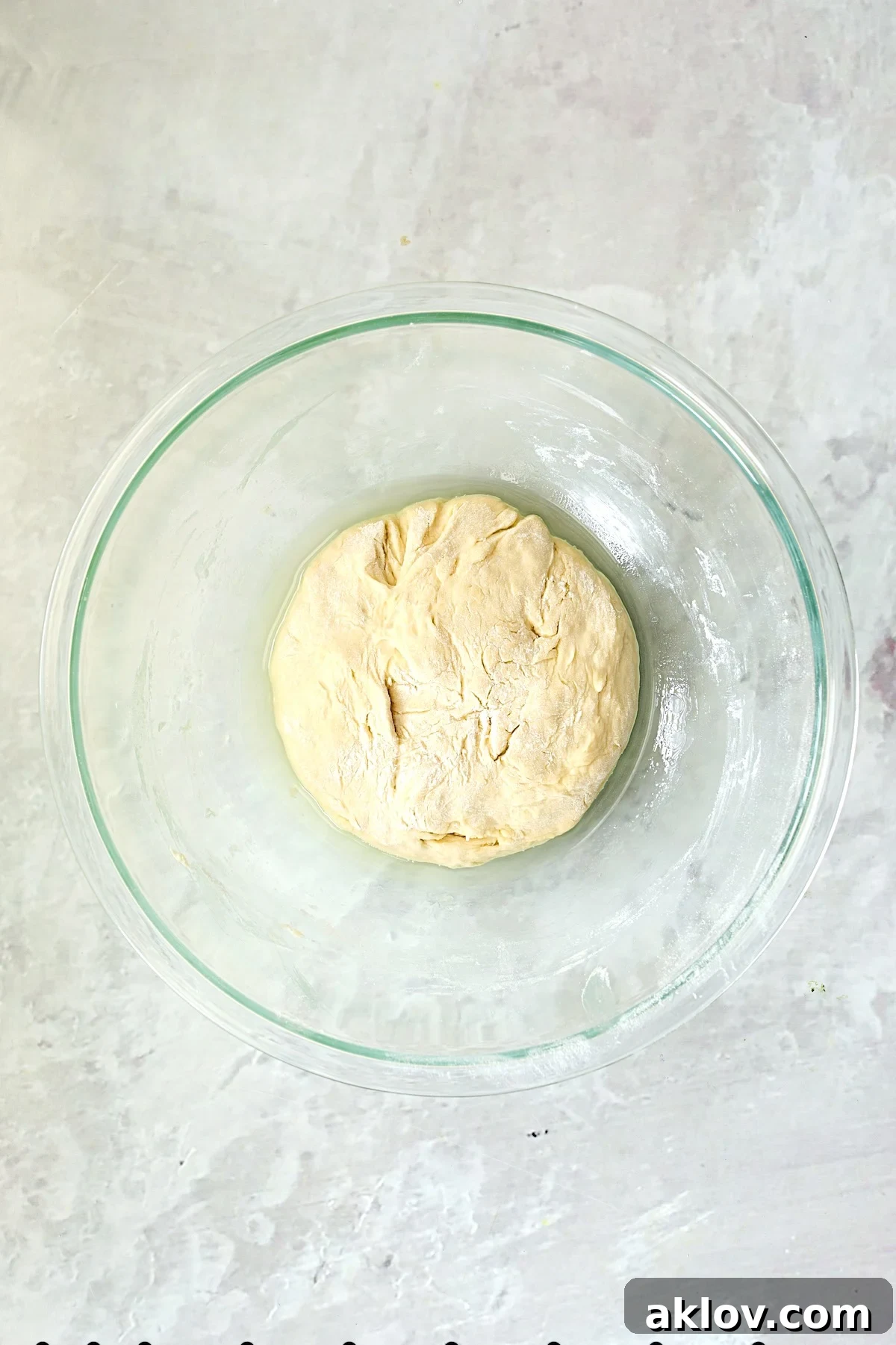 Smooth, kneaded pizza dough in a glass bowl, before its resting period.