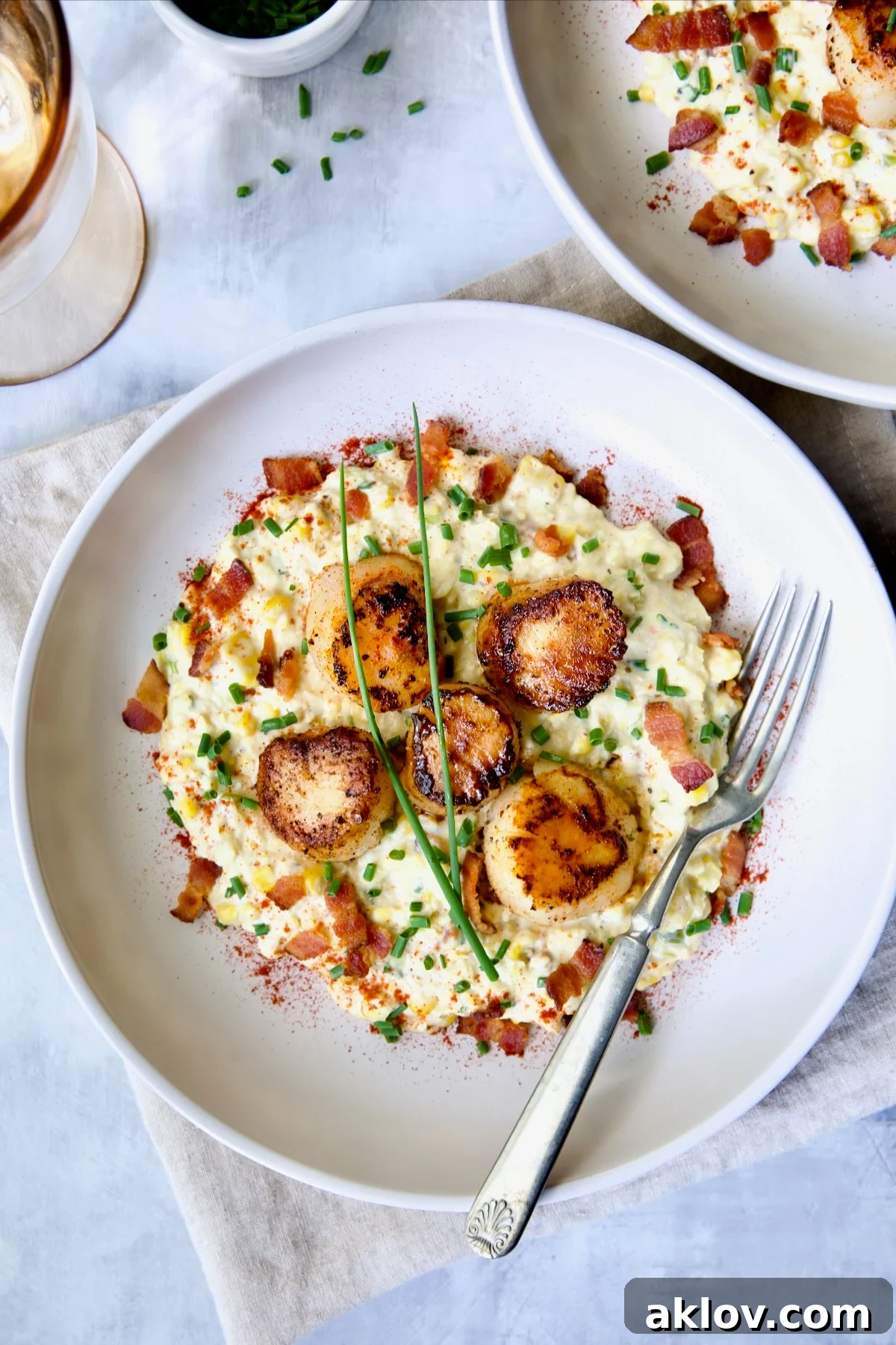 One serving of Seared Sea Scallops with Smoky Sweet Corn Puree on white plate with fork.