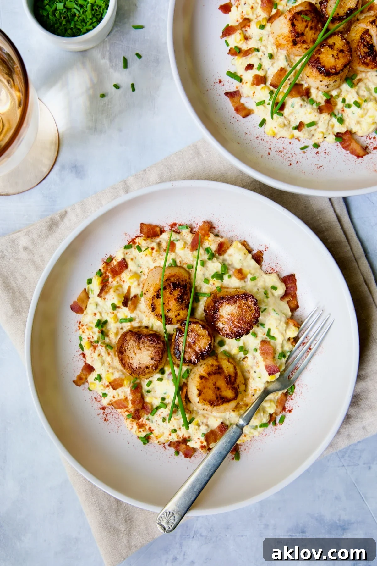 Two servings of Seared Sea Scallops with Smoky Sweet Corn Puree on a white plate with fork.