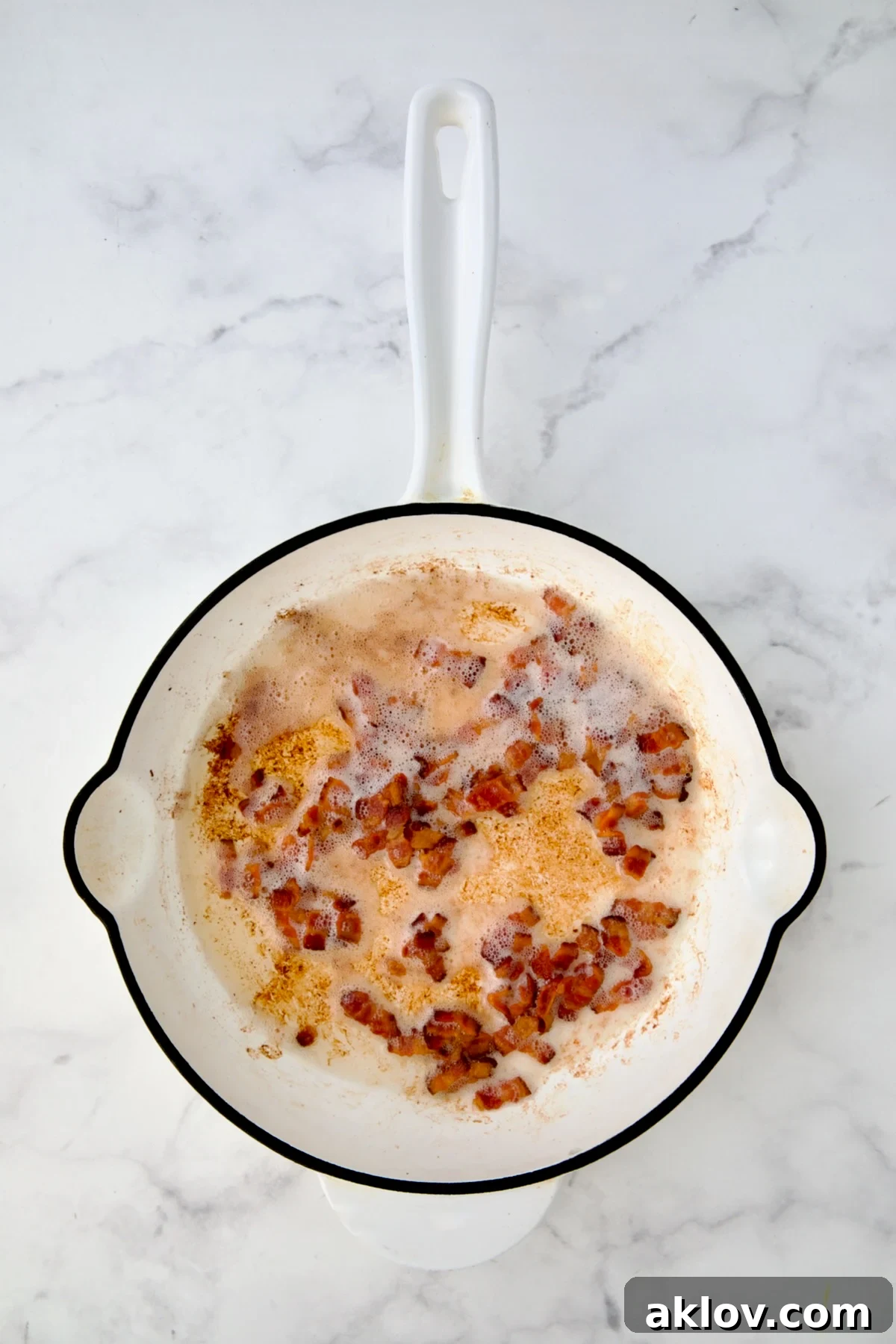 Cooked crispy bacon in white enamel cast iron skillet.