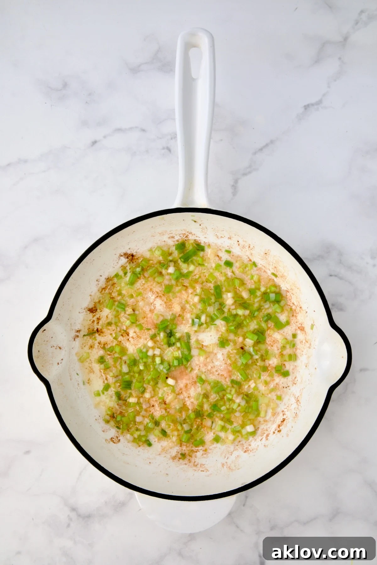Cooked scallions in white enamel cast iron skillet.