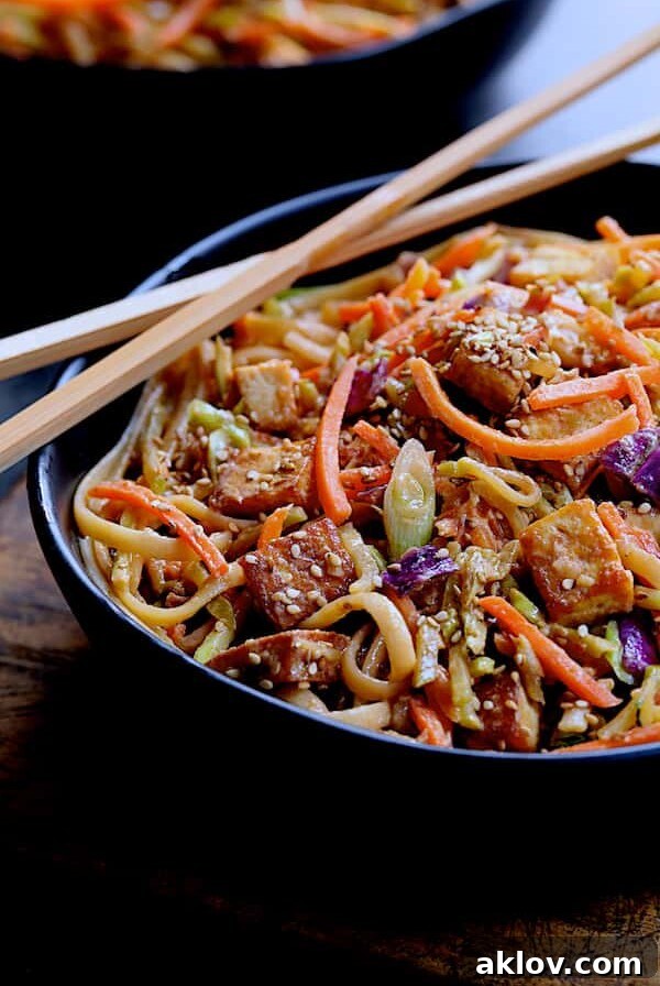 Thai Sesame Noodles with Tofu and Vegetables in black bowl with chopsticks.
