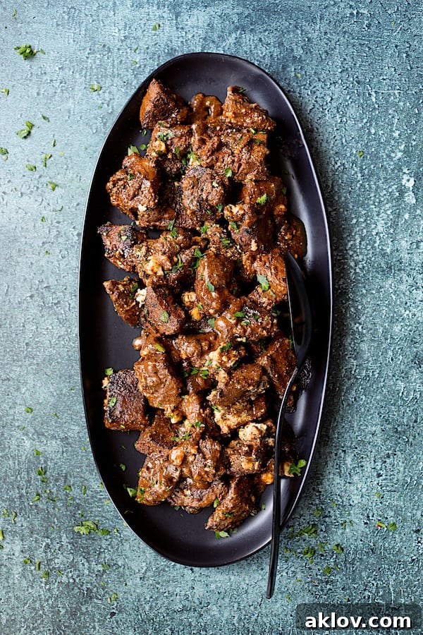 Overhead shot of Buttery Blackened Steak Bites served on a black platter, with the Gorgonzola cheese perfectly melted into the sauce.