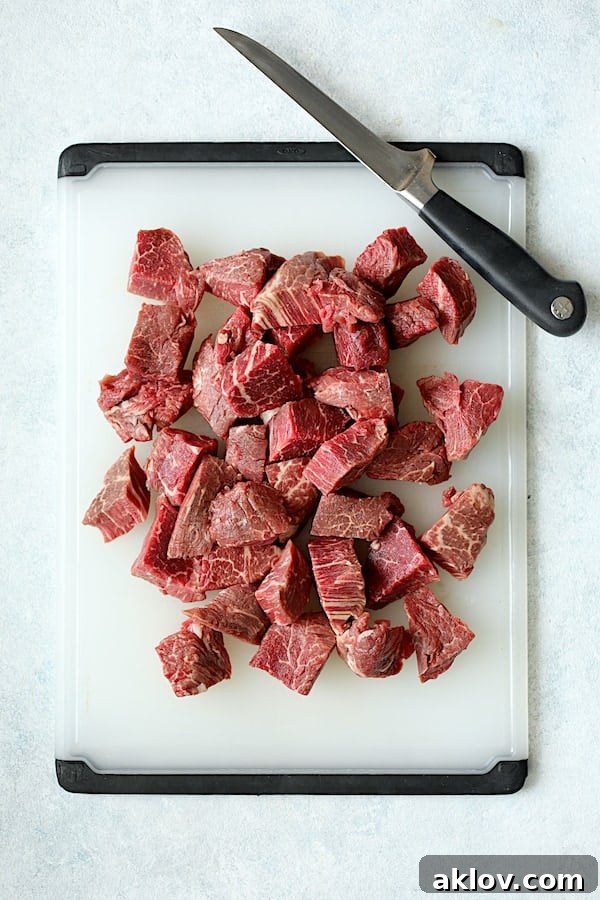 Overhead shot of the steaks meticulously cut into uniform, bite-sized pieces on a white cutting board.