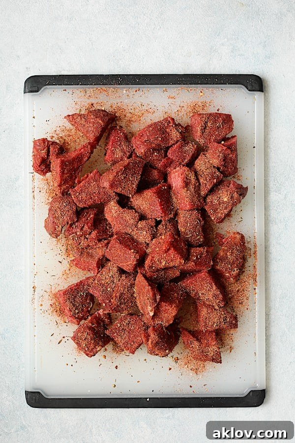 Overhead shot of steak bites on a white cutting board, generously coated and dredged in the homemade blackening mix.