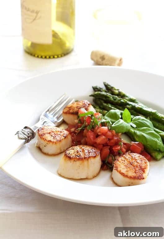 Seared Sea Scallops with Tomato, Red Onion and Balsamic Salsa with roasted asparagus on white plate.