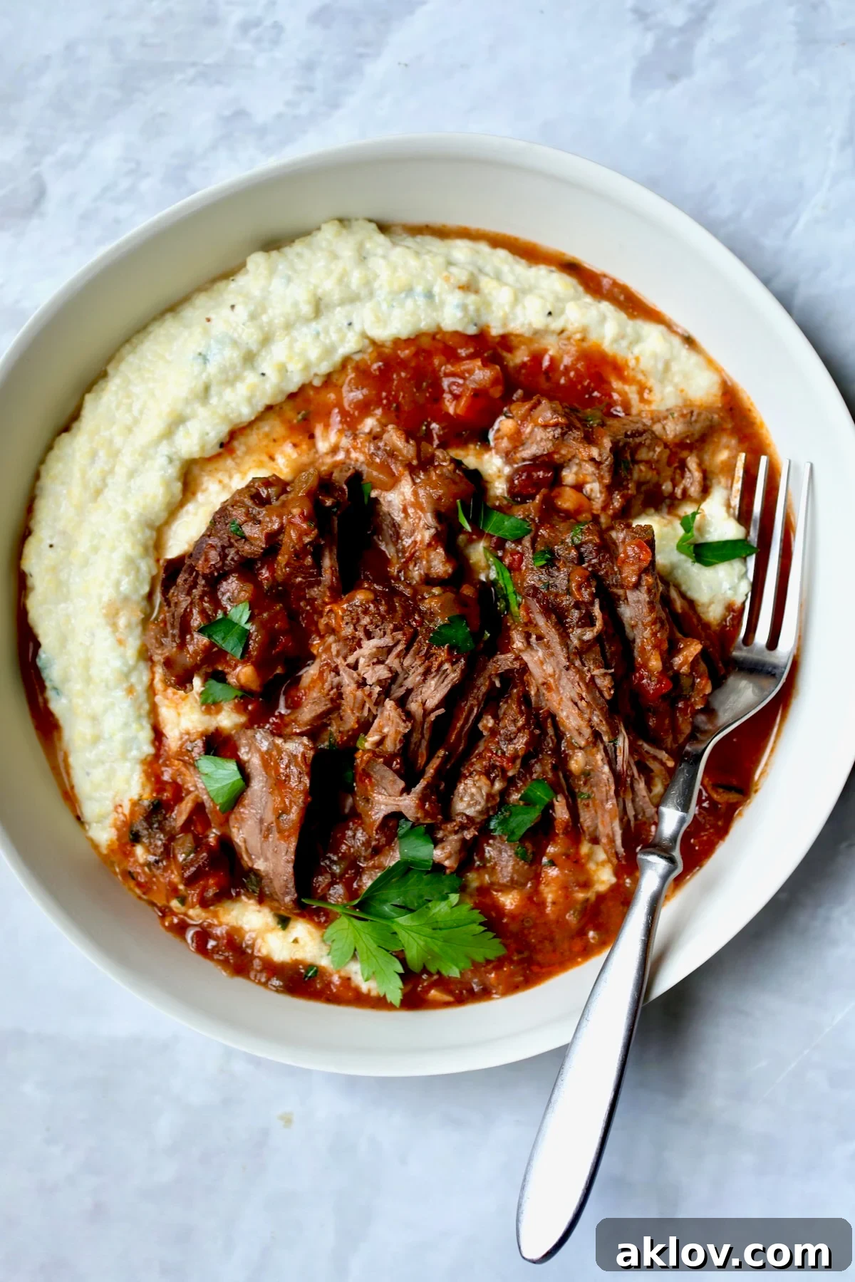 One serving of Italian Pot Roast (Stracotto) in white dinner bowl with fork.