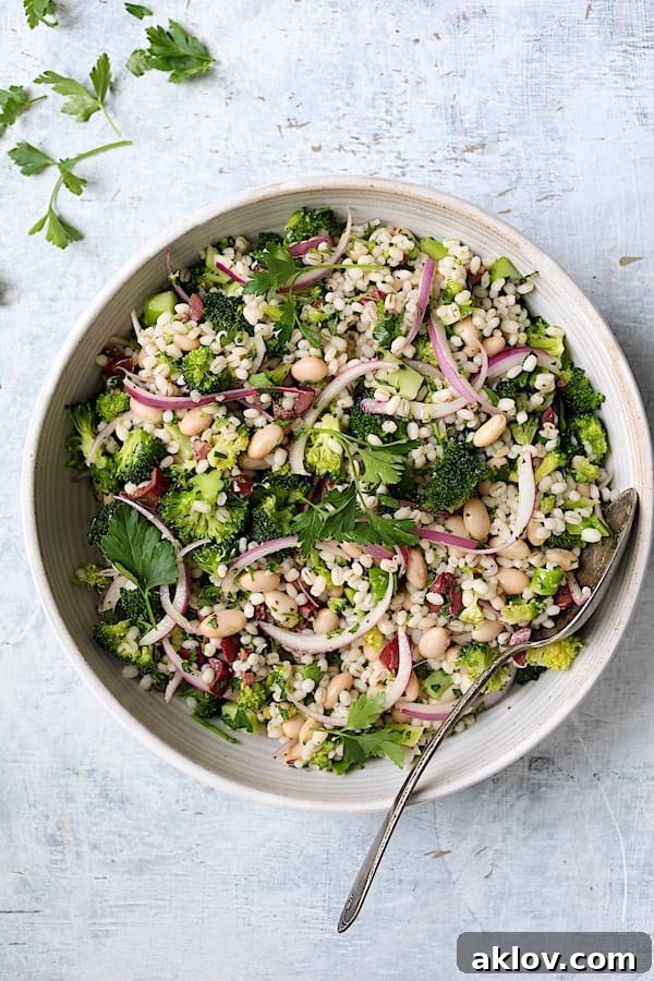 A vibrant Lemony Broccoli, Barley, and White Bean Salad in a white serving bowl, garnished with fresh parsley.
