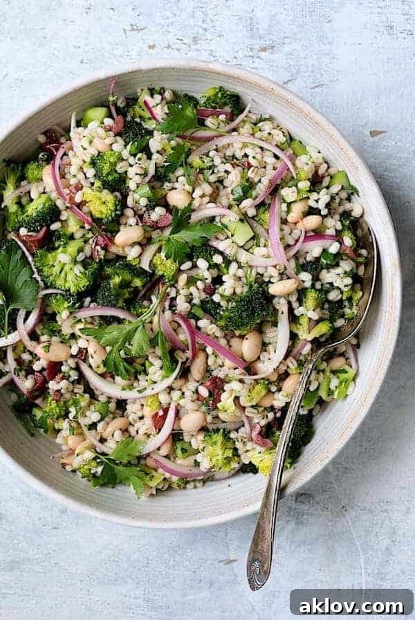 Lemony Broccoli, Barley, and White Bean Salad in a white serving bowl with a serving spoon.