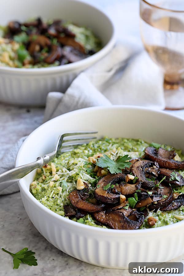 Two white bowls filled with Oven Risotto, topped with Kale Pesto and Roasted Mushrooms, and a sprinkle of fresh parsley.