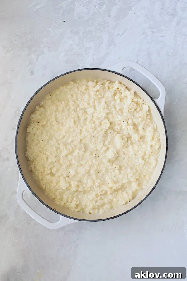 Finished risotto in a white cast iron pan, prior to the addition of kale pesto, showing its creamy texture.