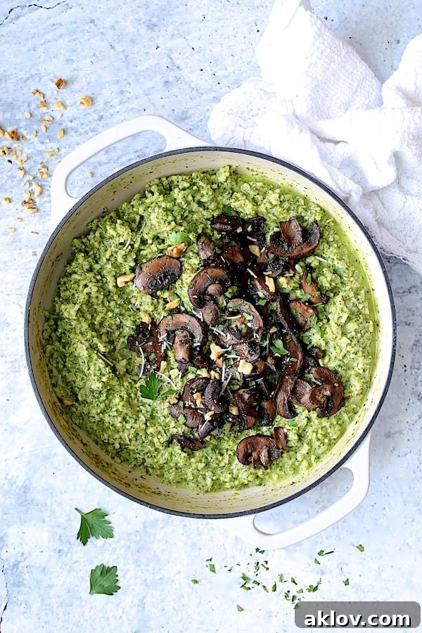 A close-up view of the Oven Risotto with Kale Pesto and Roasted Mushrooms presented in a white skillet, garnished and ready to serve.