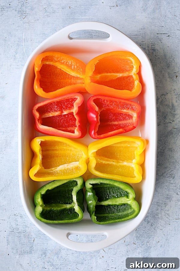Zesty Chicken and Rice Pepper Boats 4 Photo of four peppers cut in half in white baking dish to form eight halves.